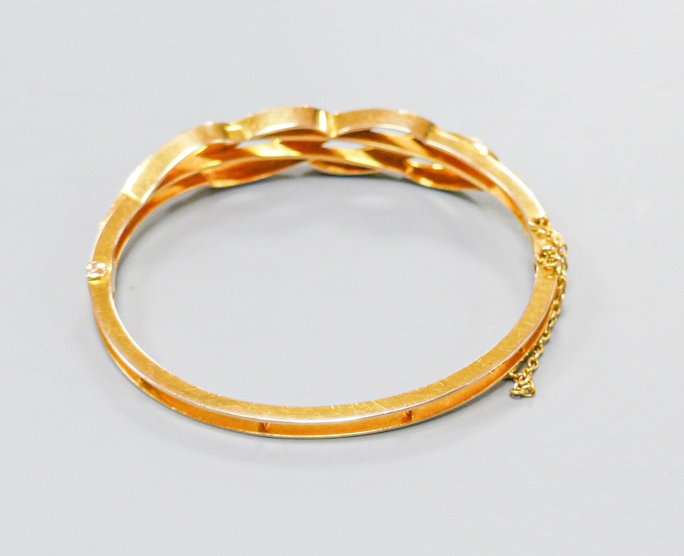 A boxed Edwardian yellow metal, graduated turquoise and seed pearl set hinged bangle, interior diameter 55mm, gross weight 15.5 grams.